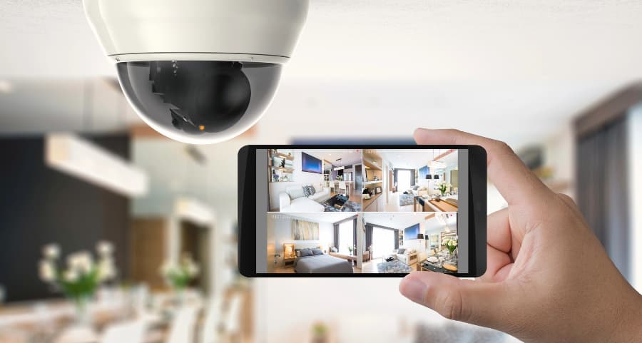 Homeowner holding smartphone with video feed from security cameras in Los Angeles